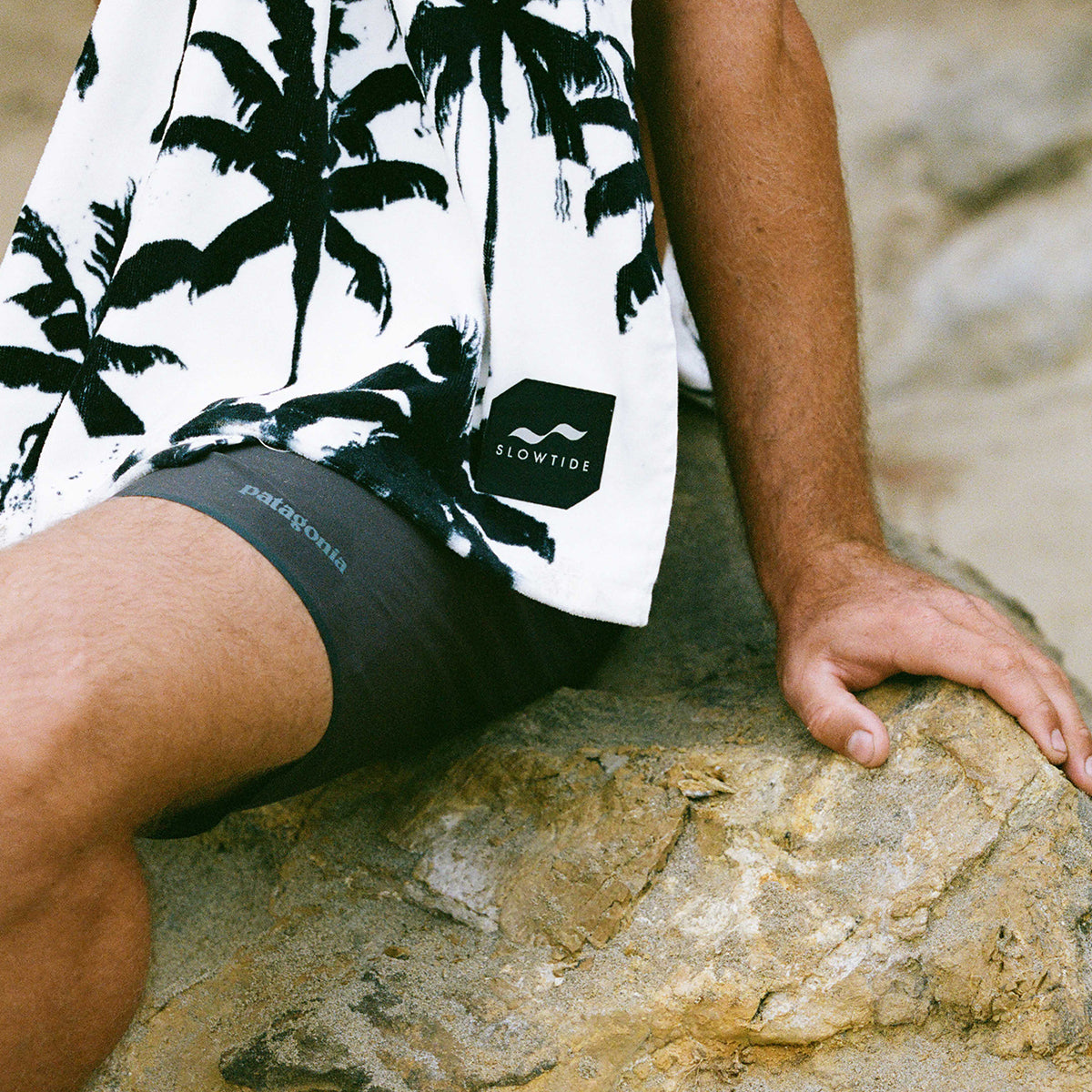 Palm tree print shirt and shorts with absorbent beach towel nearby.