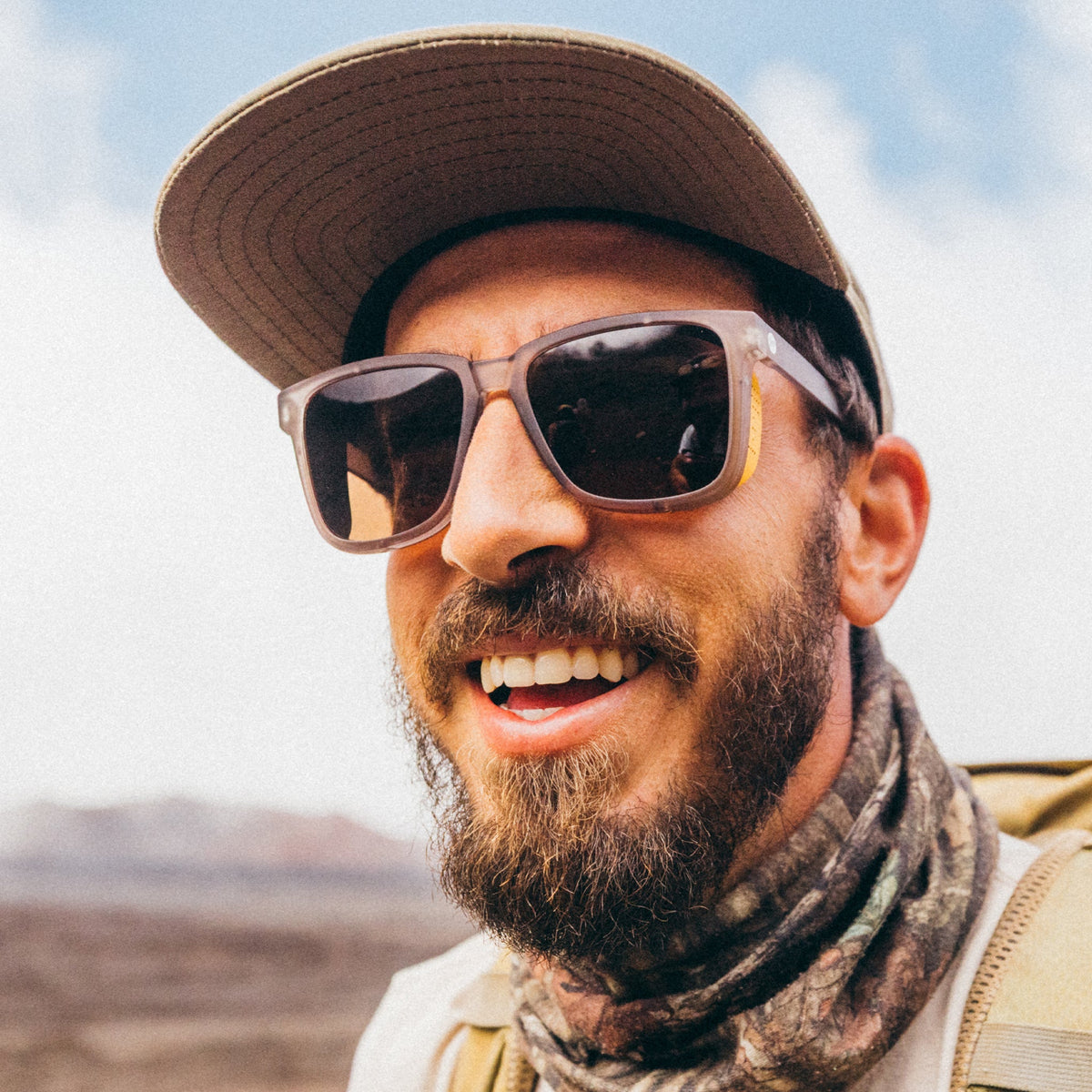 Man wearing sunglasses and a cap with a blurred natural background