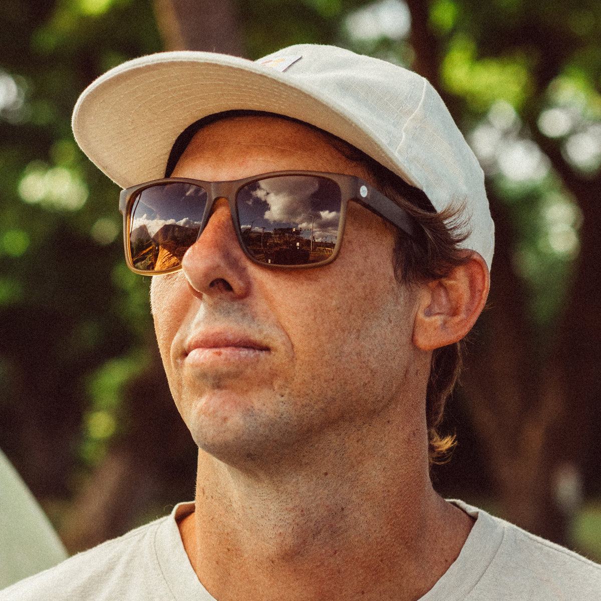 Man wearing sunglasses and a cap with a blurred green background