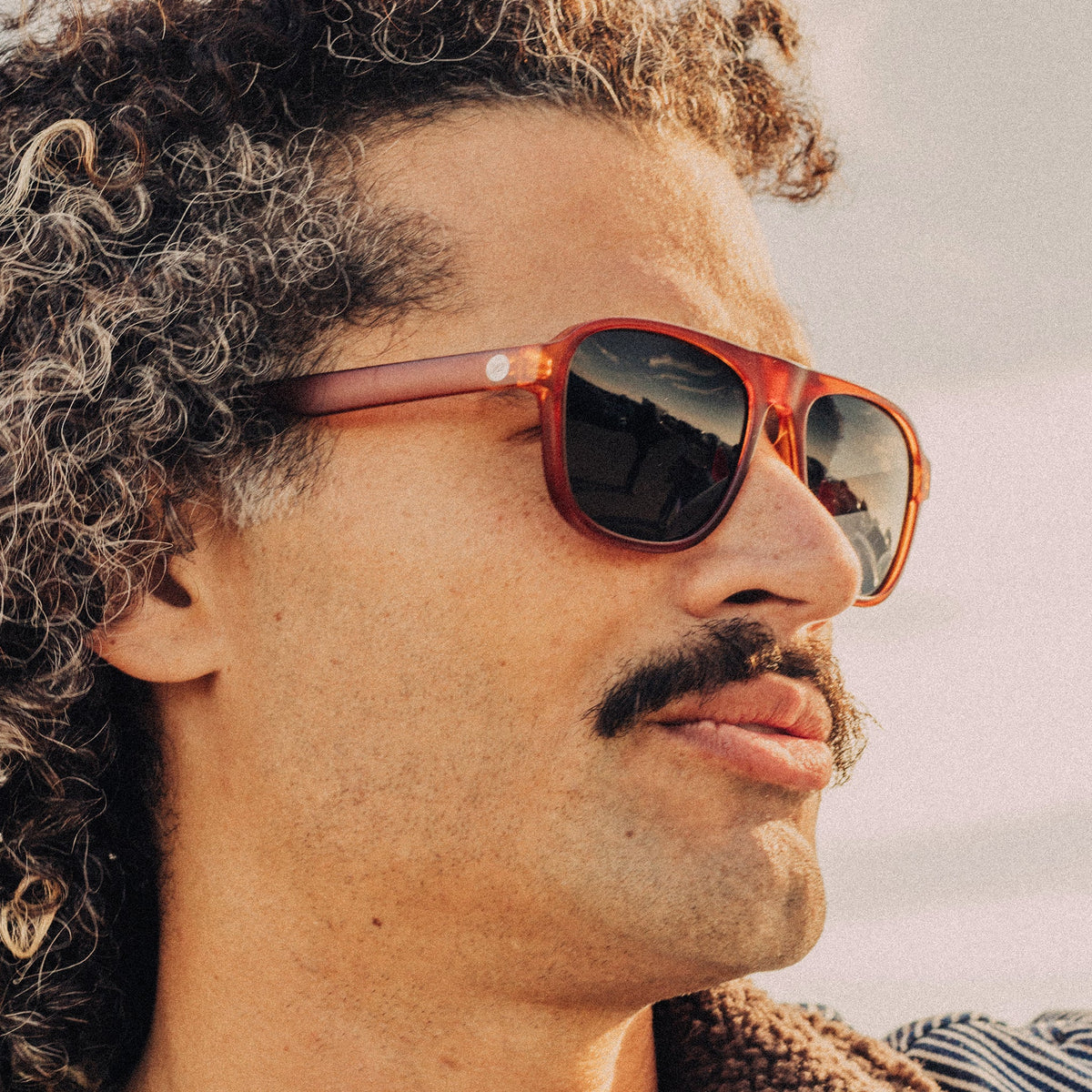 Man wearing red sunglasses with a blurred natural background