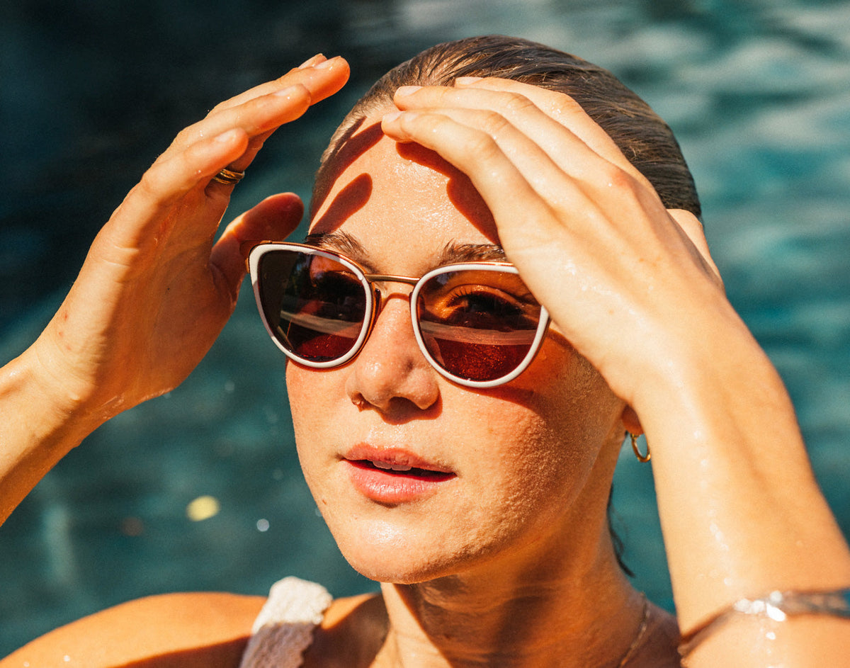 STORY girl pushing hair out of her face in pool wearing sunski catalina sunglasses