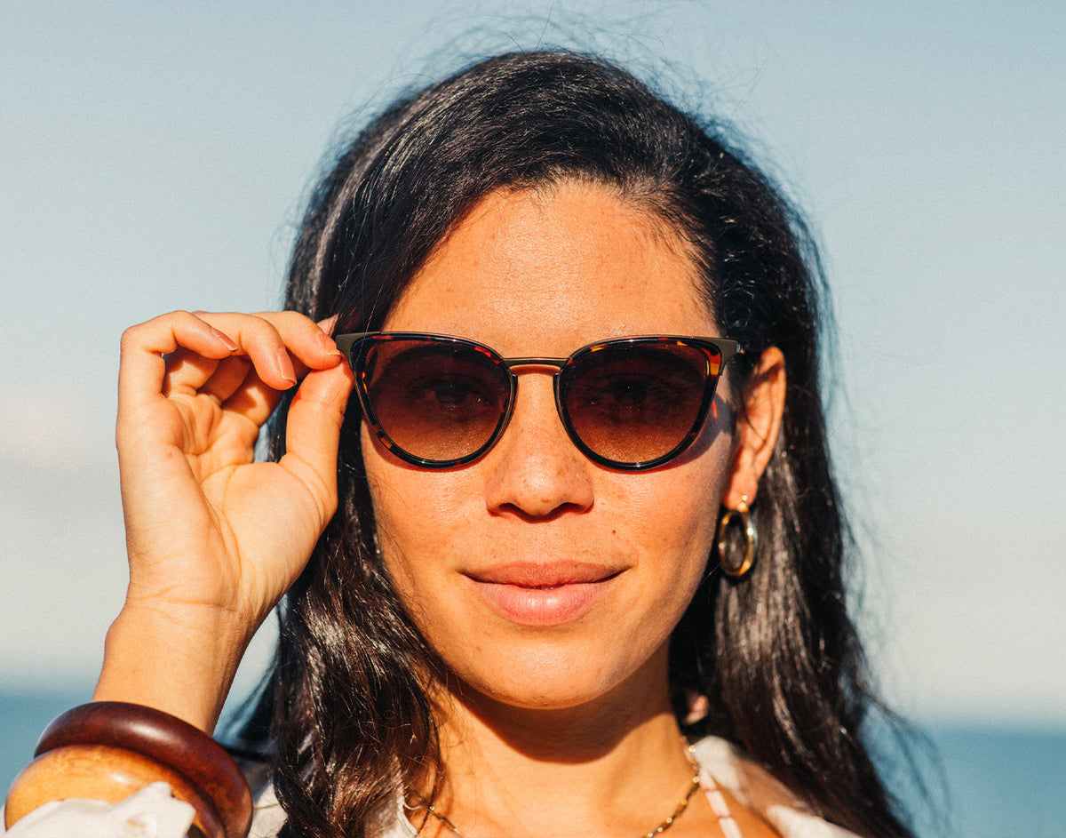 STORY girl holding sunski catalina sunglasses on face