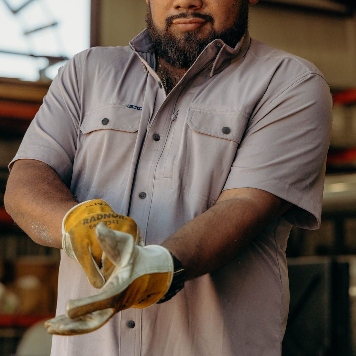 man putting on work gloves while wearing the Big Iron shirt