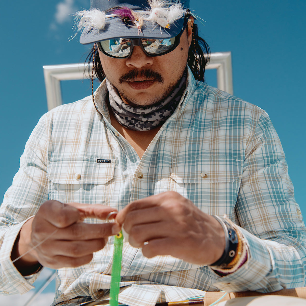 Man tying on a fly while wearing the Nervous Water shirt