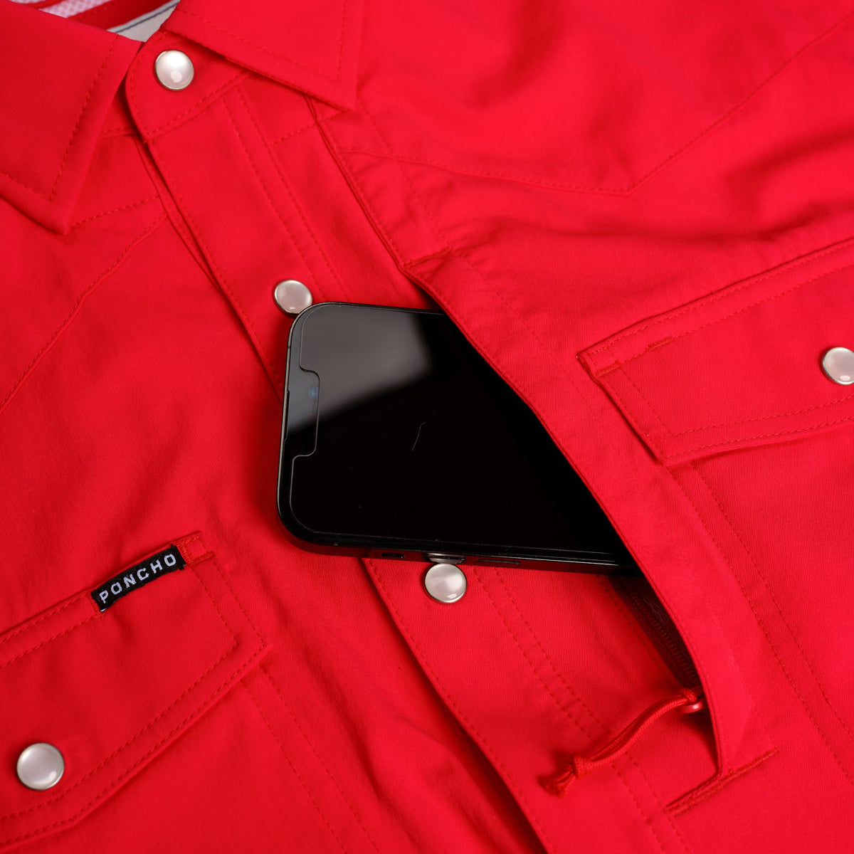 closeup of iphone going into chest pocket of red shirt