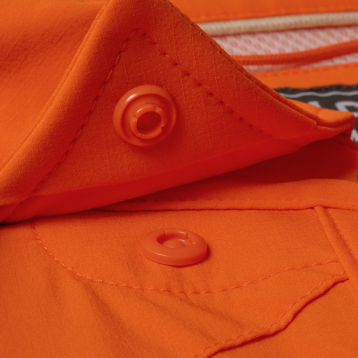 Close-up of orange fabric and snap button detail on The Dick Cheney shirt