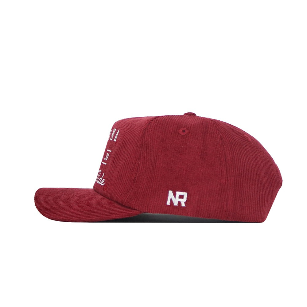 Side view of the Alabama Vintage Cord Hat by No Rivals, a red unstructured corduroy cap with white NR embroidery, flat brim, visible stitching, and a classic snapback closure.