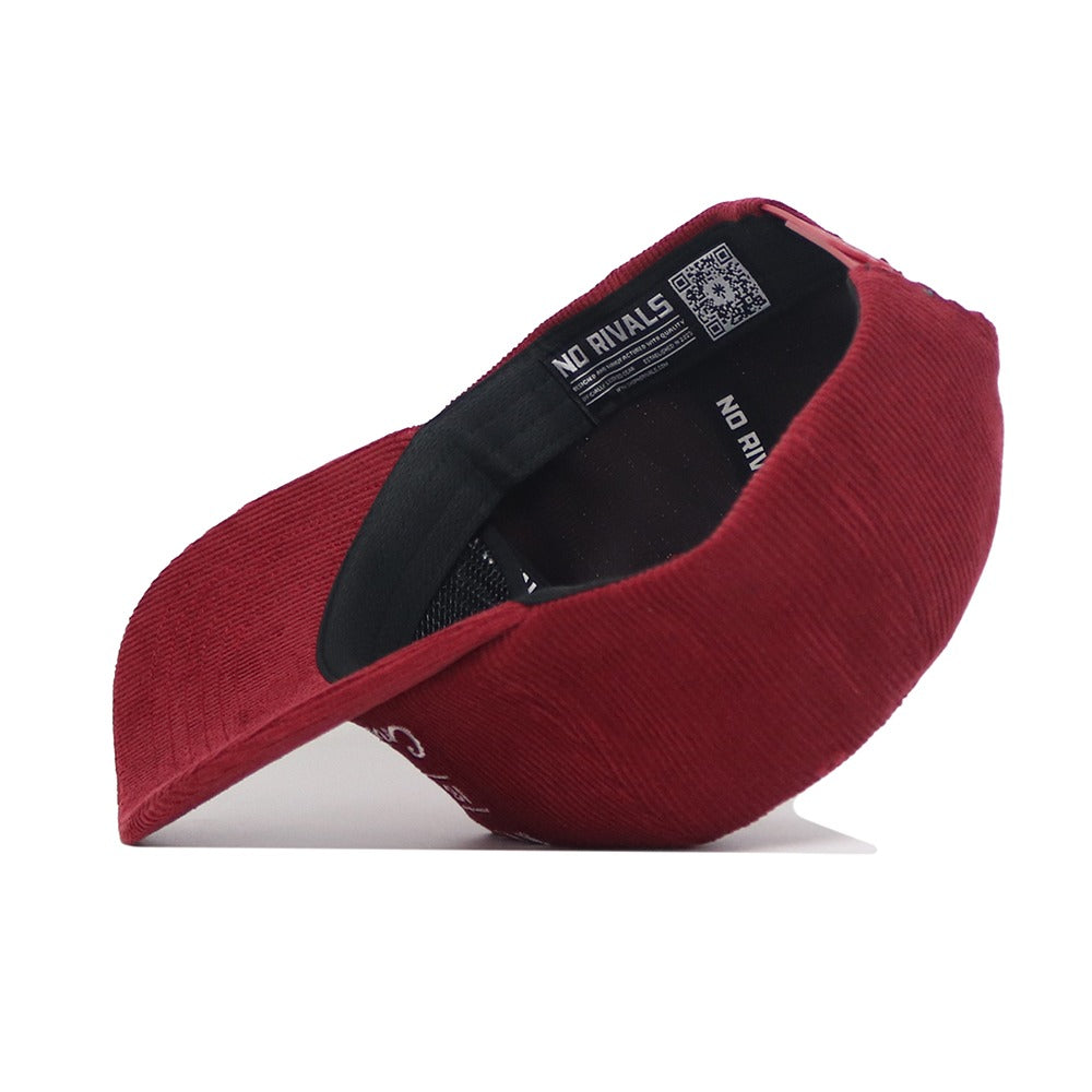 The Alabama Vintage Cord Hat by No Rivals is pictured upside down, showing its black inner band, label, and QR code. The unstructured shape, curved brim, and red corduroy texture are clearly visible.