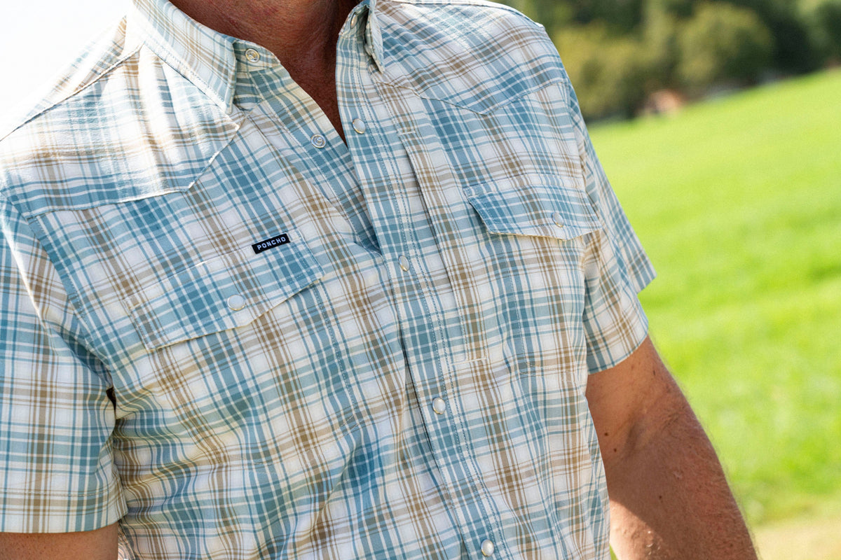 Close-up of a man wearing The Sandbar shirt with a green and white plaid pattern outdoors on a sunny day