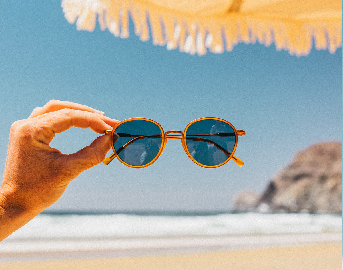 STORY baia tangerine midnight held in a woman's hand with the beach in the background