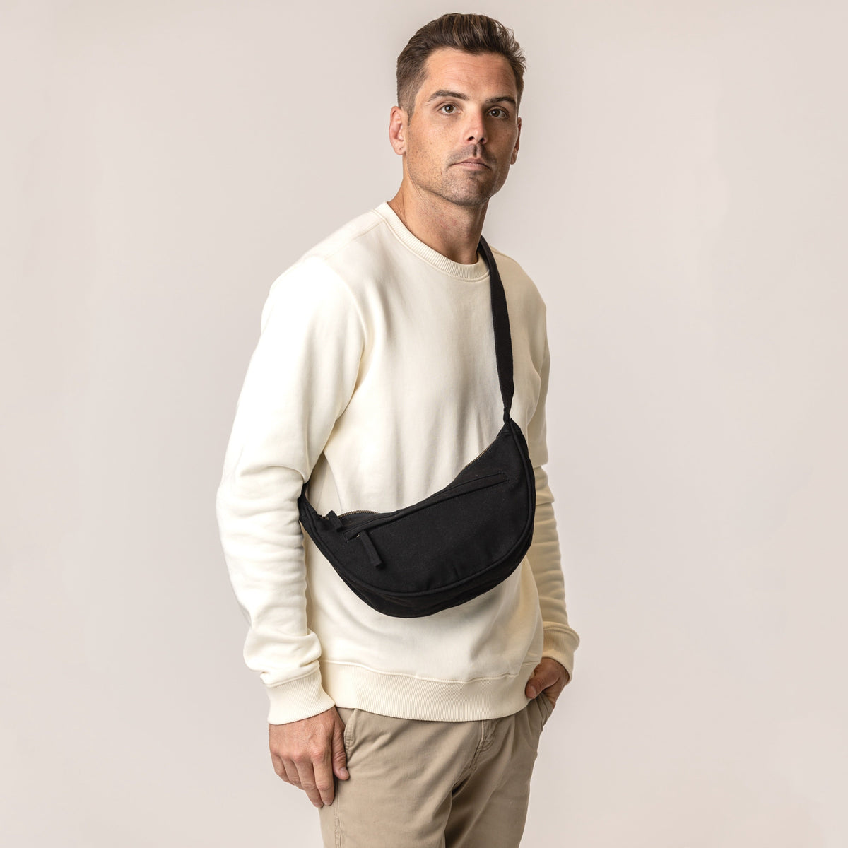 Man wearing a crossbody bag in black#color_ivory-black