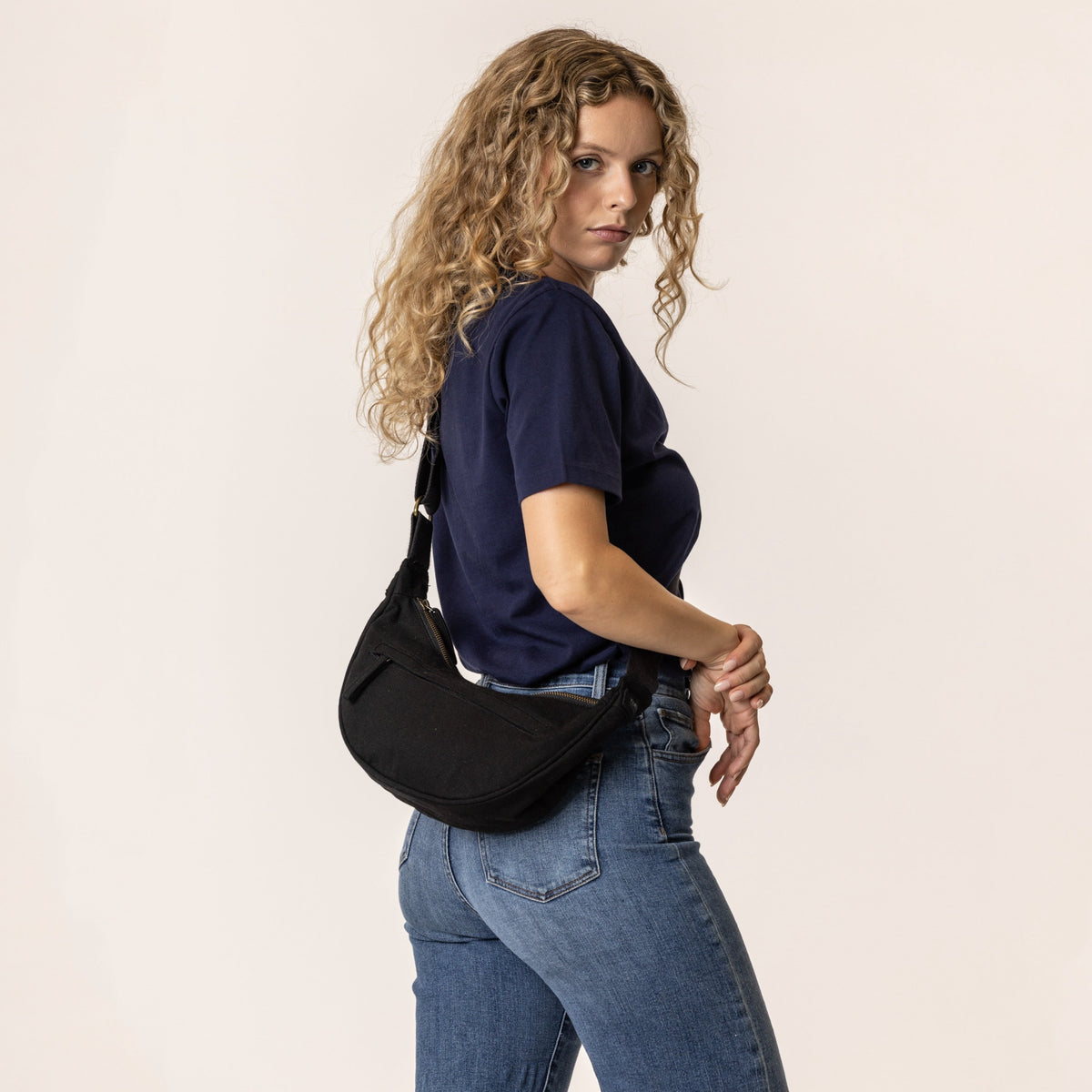Woman wearing a black crossbody bag#color_ivory-black