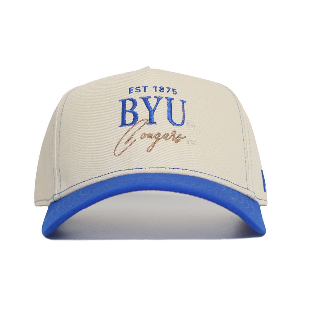 The No Rivals BYU Vintage Hat features a beige and blue snapback design with "BYU Cougars, EST 1875" embroidered in blue and brown. Made from high-quality cotton and officially licensed for authentic Cougar pride.