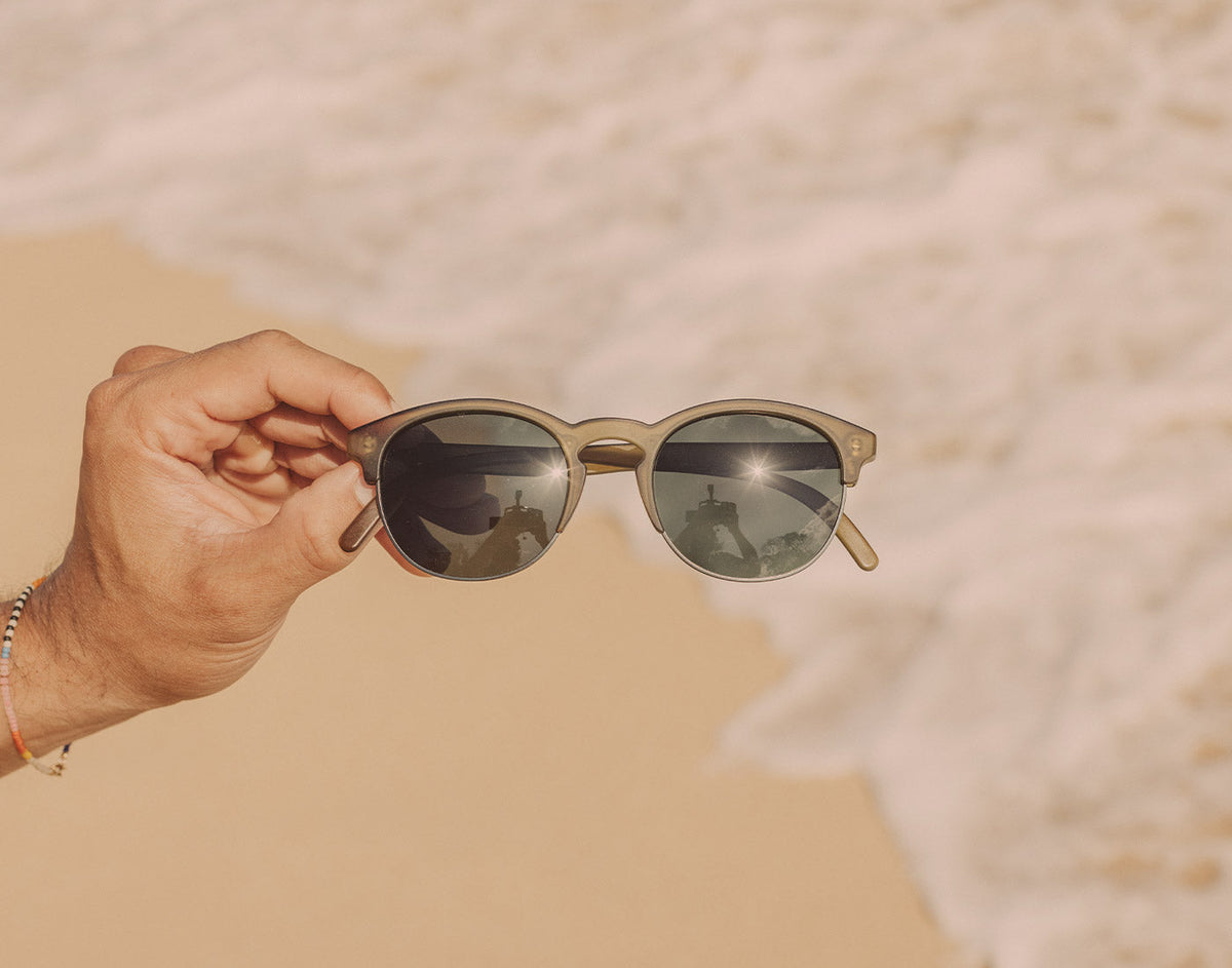 STORY hand holding sunski avila sunglasses on the beach