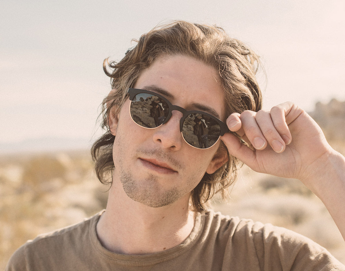 STORY guy holding sunski avila sunglasses up to face