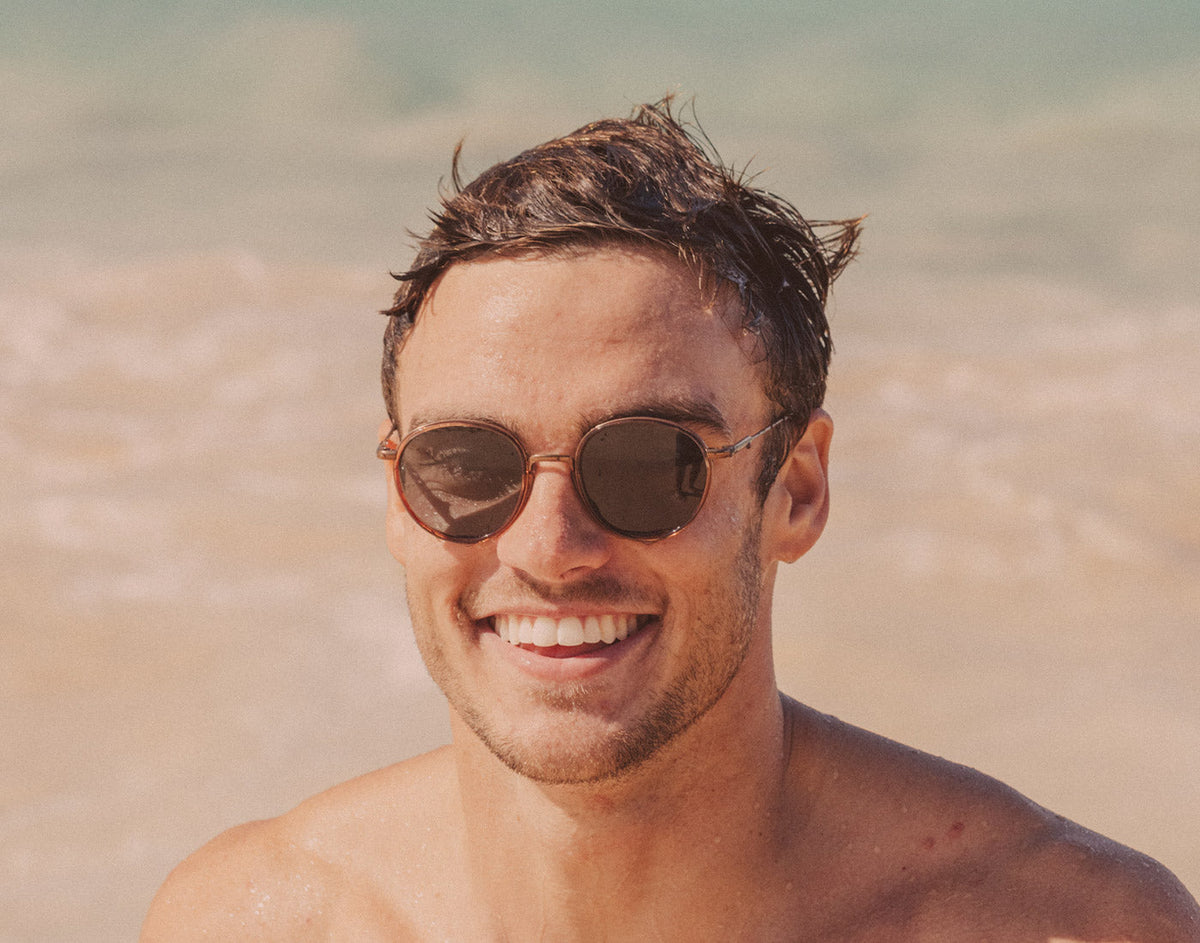 STORY guy smiling on the beach wearing sunski baia sunglasses