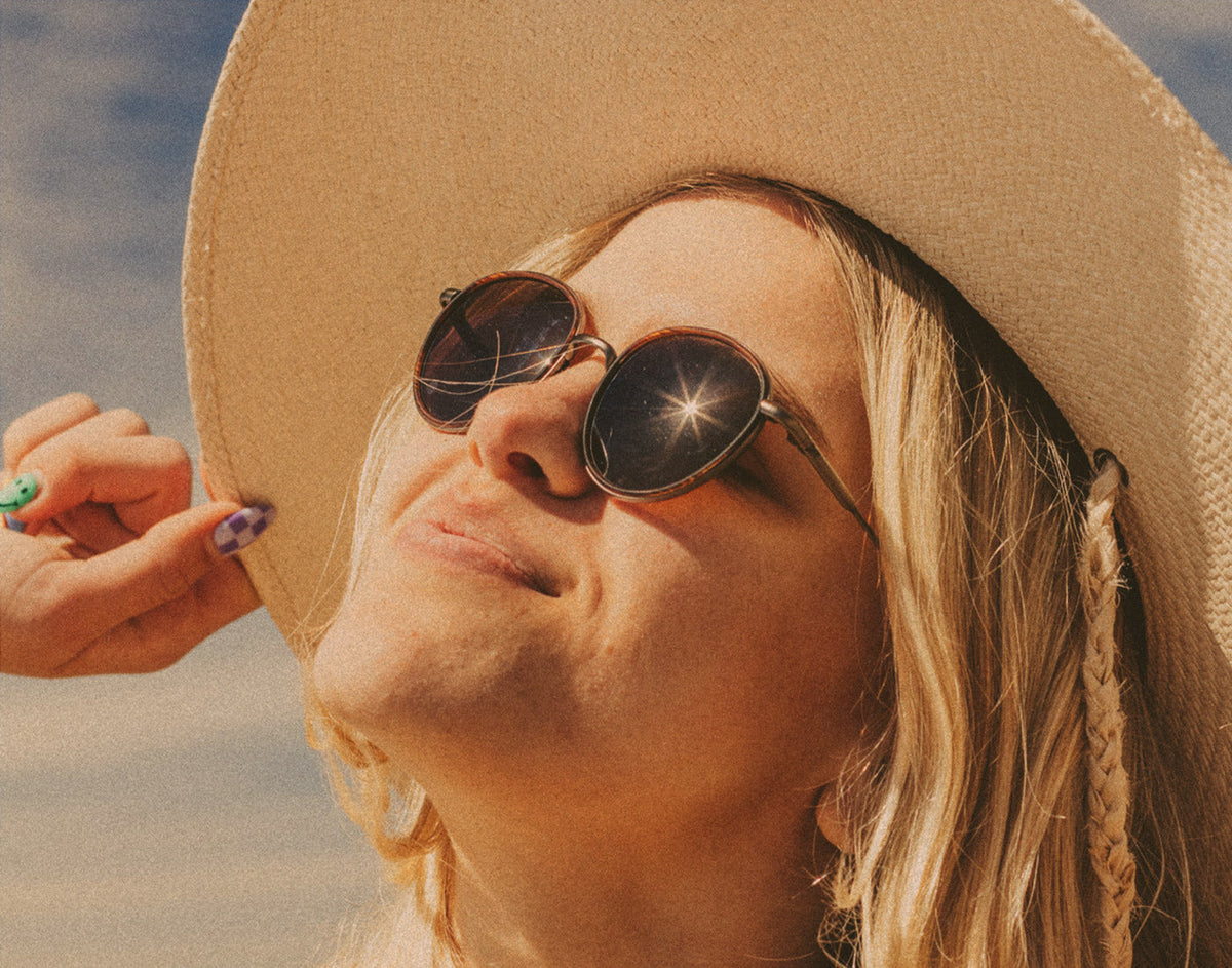 STORY woman in hat basking wearing sunski baia sunglasses