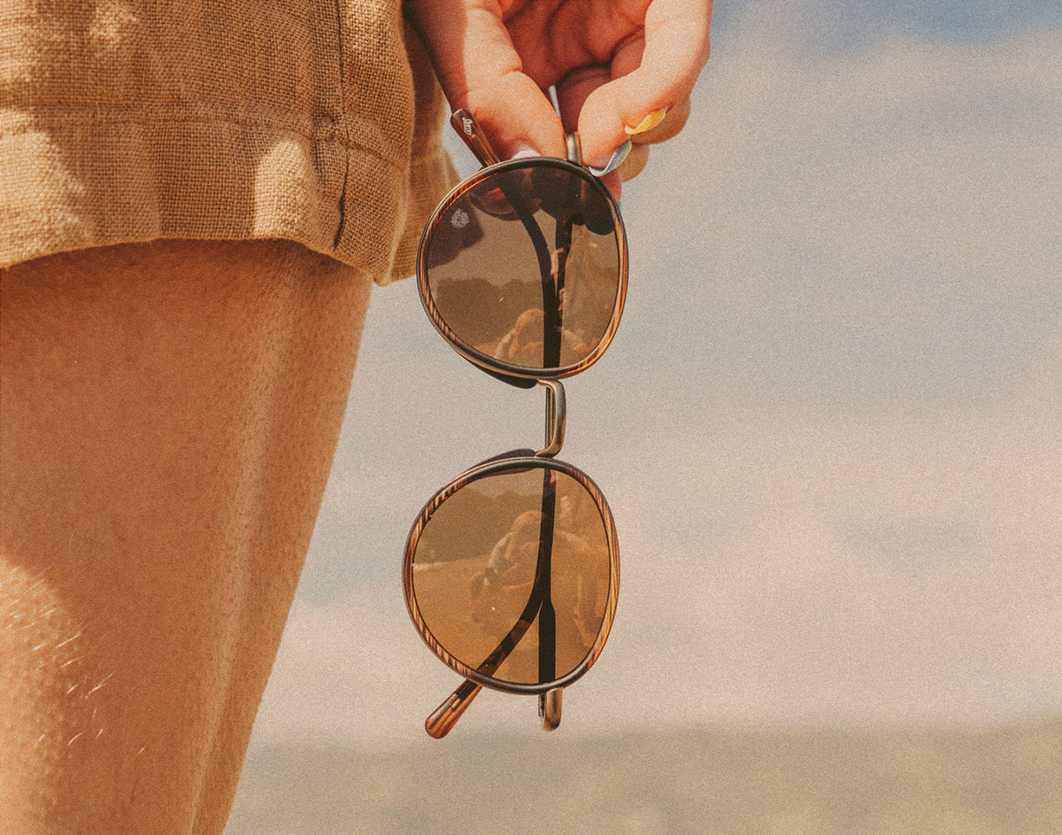 STORY hand holding sunski baia sunglasses vertically