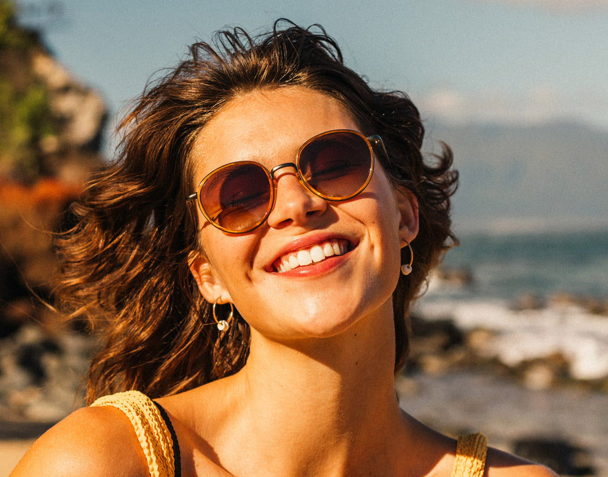 STORY woman laughing with wind blowing wearing sunski baia sunglasses
