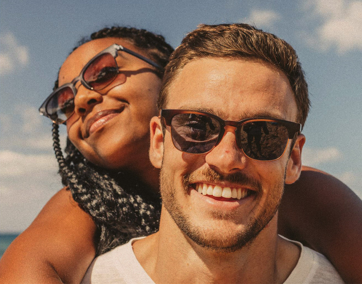 STORY girl on guy&#39;s back wearing sunski cambria sunglasses