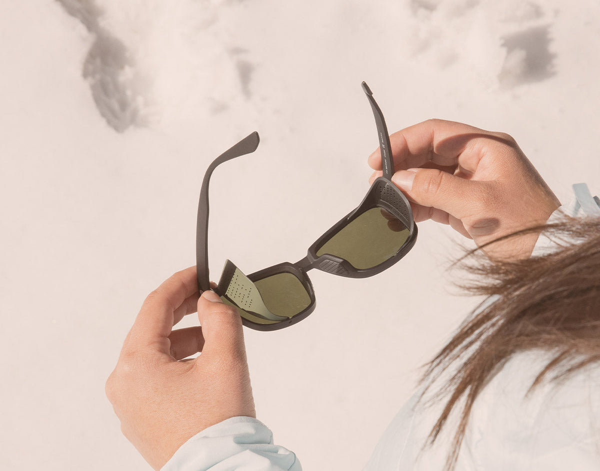 STORY hands holding unfolded sunski couloir sunglasses