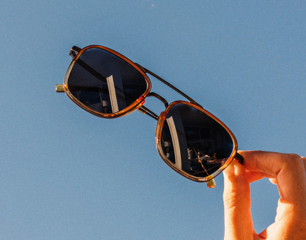 STORY hand holding sunski estero sunglasses in the air