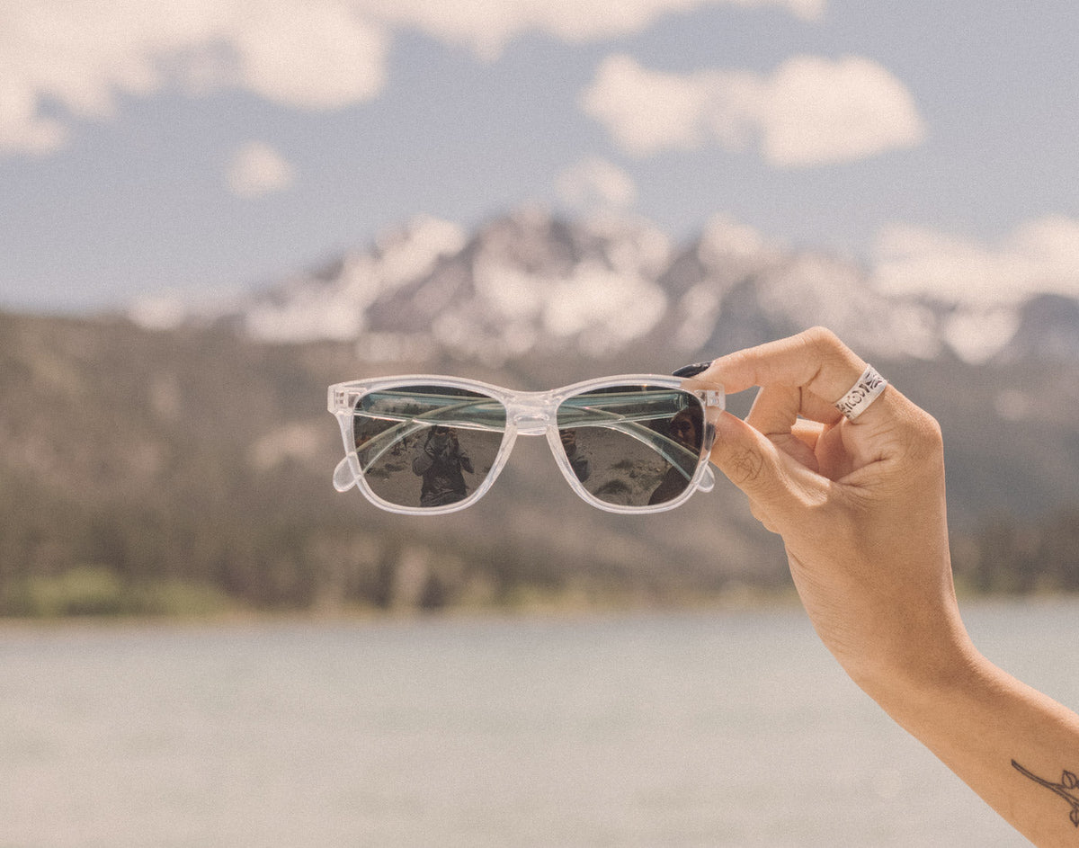 STORY hand holding sunski headland sunglasses in front of the mountains