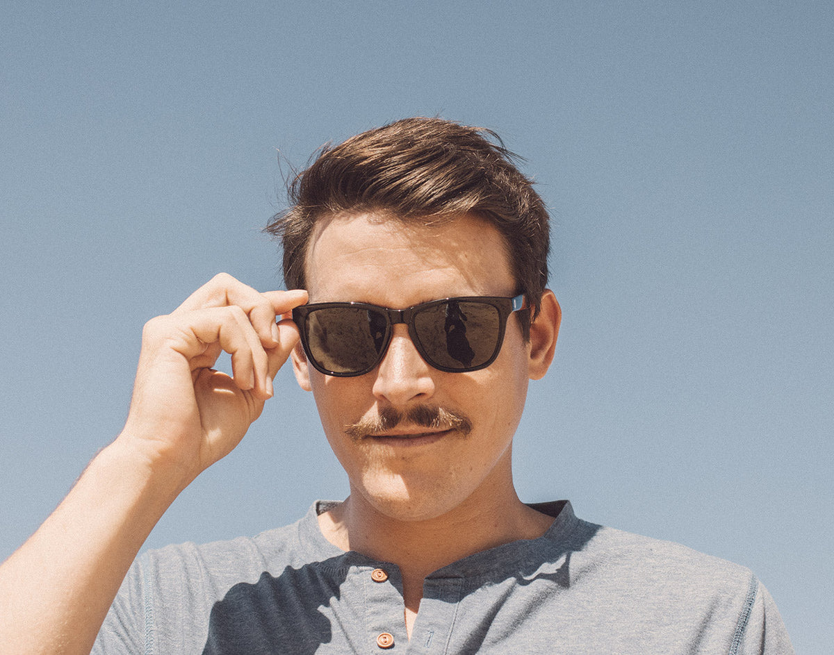 STORY guy holding sunski headland sunglasses on face