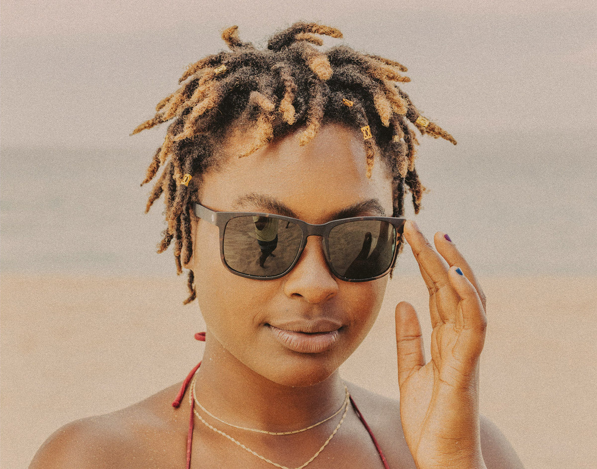 STORY woman wearing sunski kiva sunglasses with hand holding them