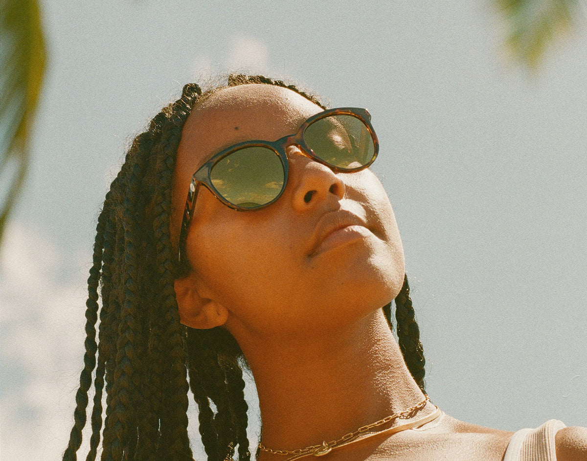 STORY woman looking up toward the sun wearing sunski makani sunglasses