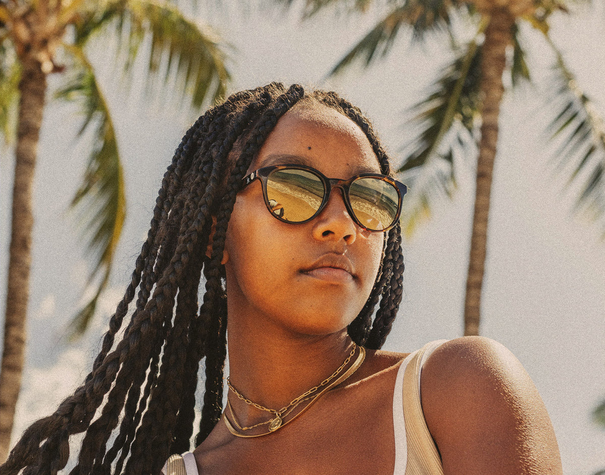 STORY girl in tropical setting wearing sunski makani sunglasses