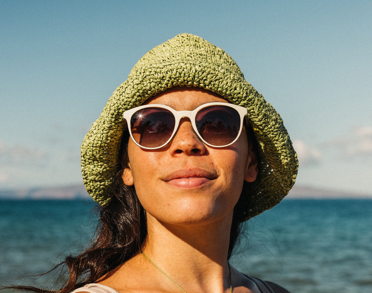 STORY woman basking in a hat and sunski makani sunglasses