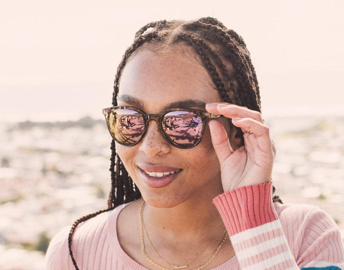 STORY girl with hand holding sunski makani sunglasses to face