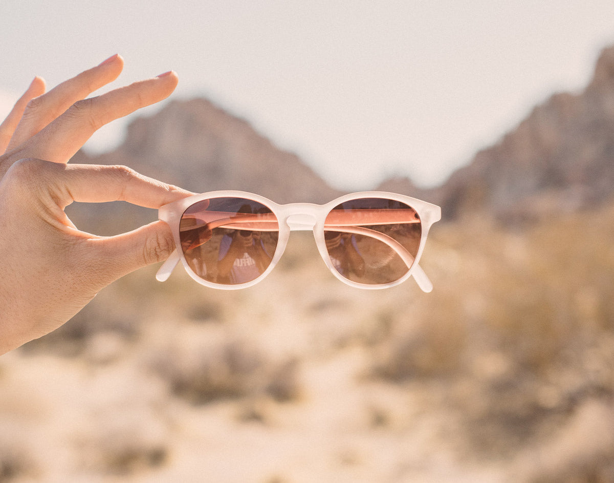 STORY hand holding sunski yuba sunglasses in desert