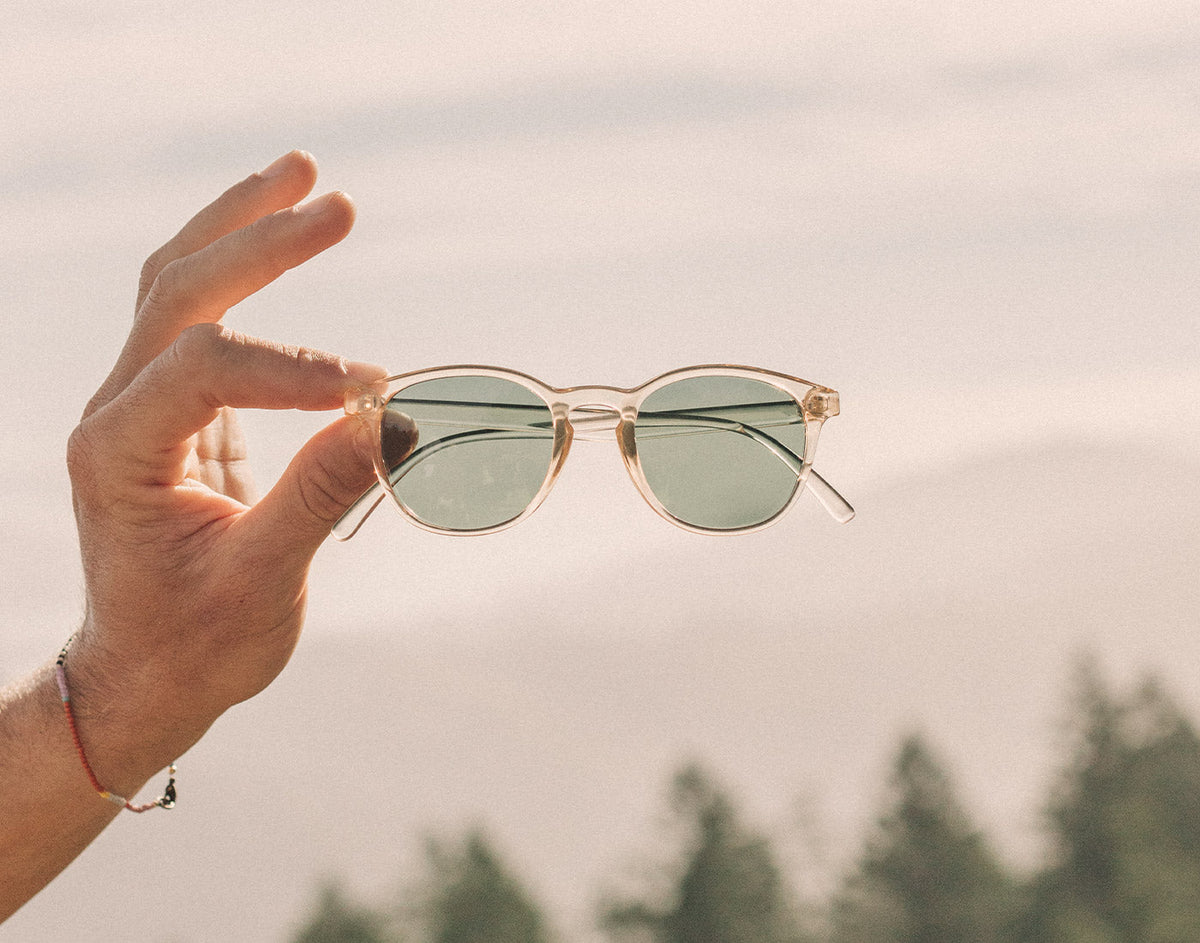 STORY hand holding sunski yuba sunglasses in mountains