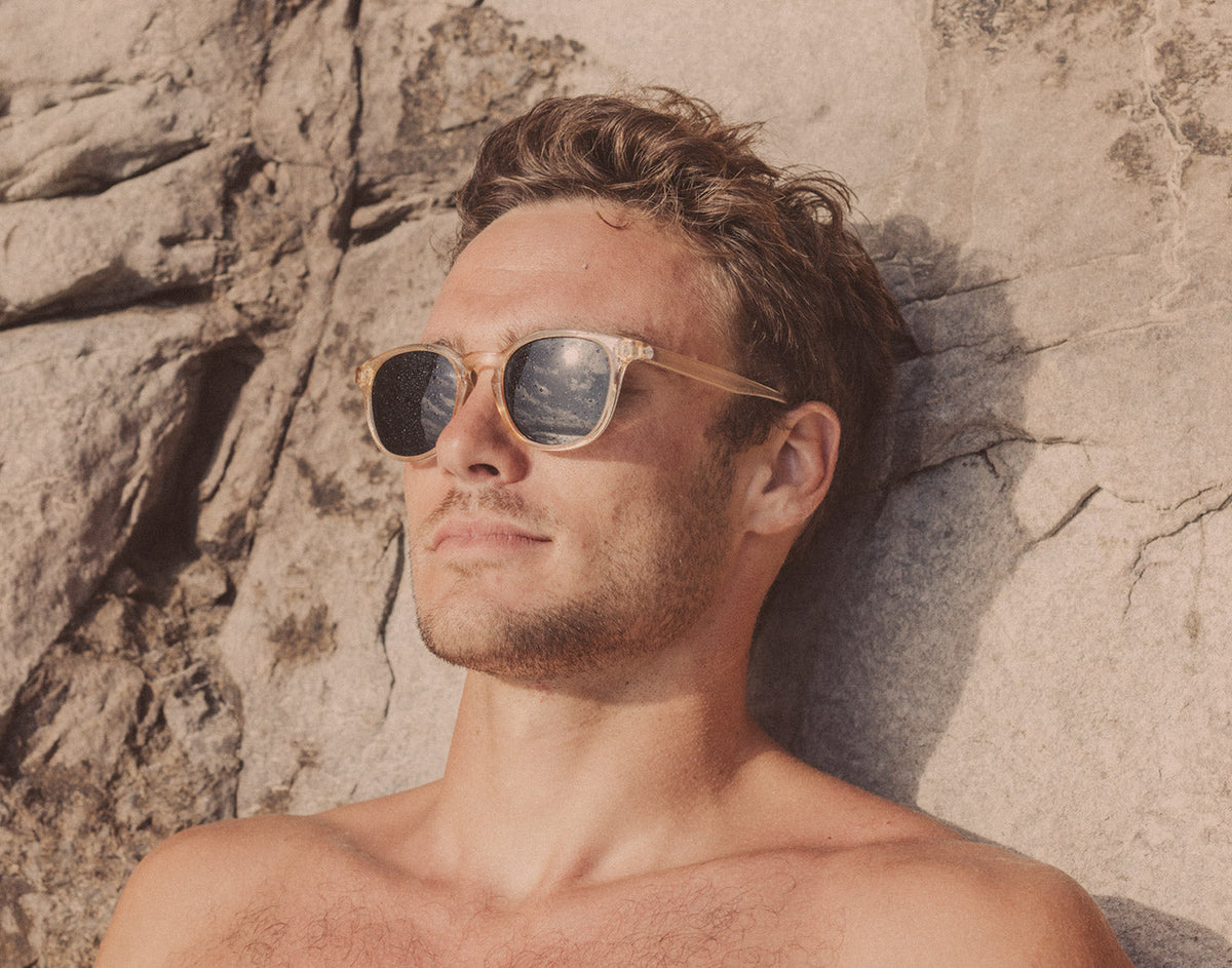 STORY guy leaning on rock wearing sunski yuba sunglasses