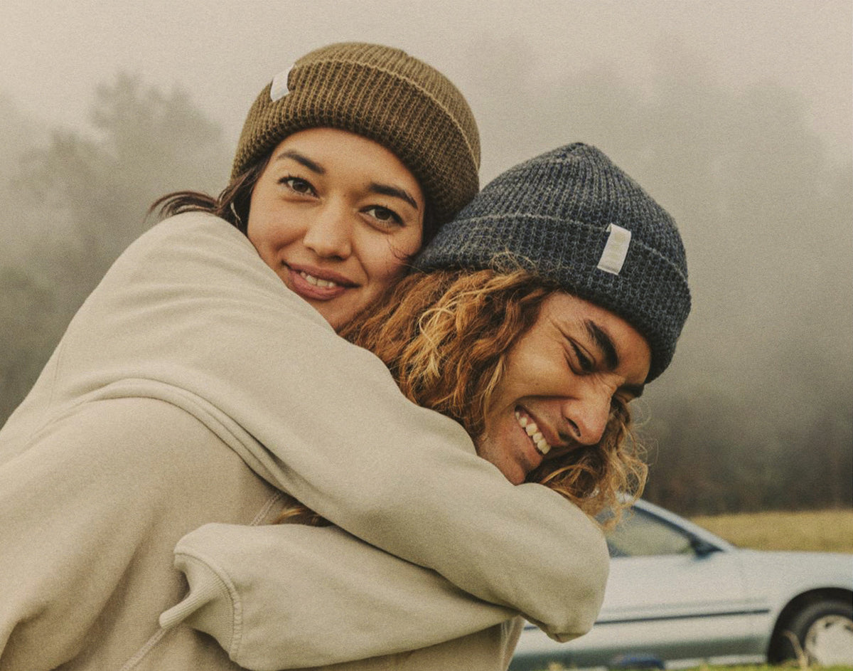 STORY woman on man&#39;s back wearing sunski winter sun beanie