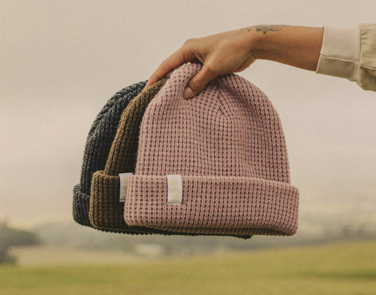 STORY hand holding all three sunski winter sun beanies