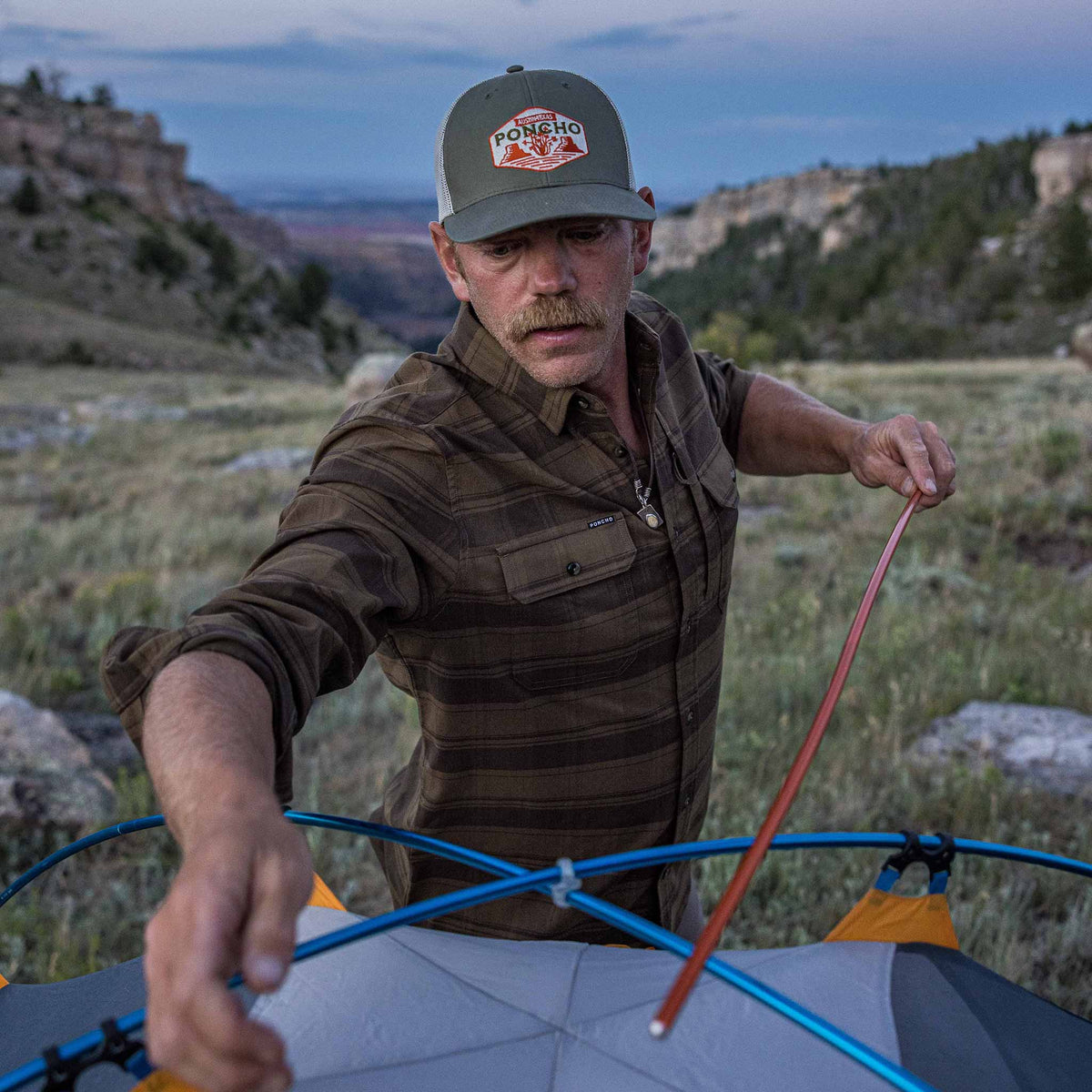 guy wearing flannel setting up tent