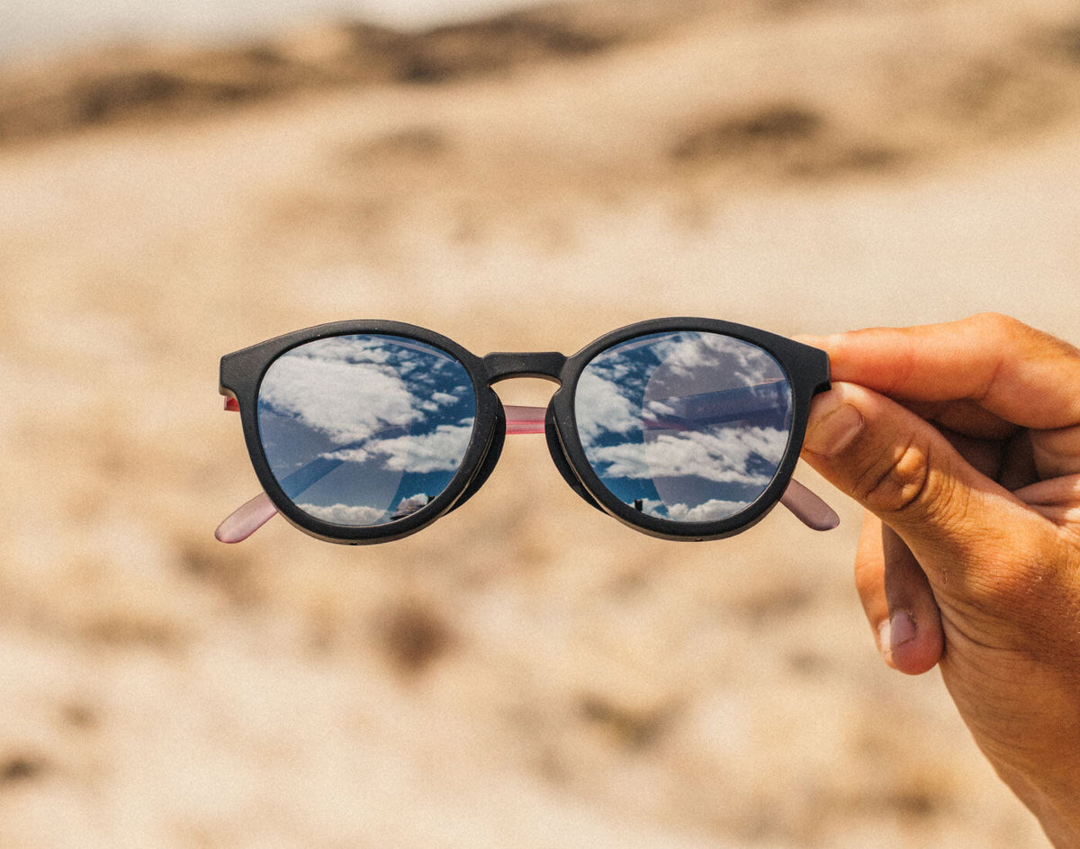 STORY Sunglasses held up with a desert landscape in the background