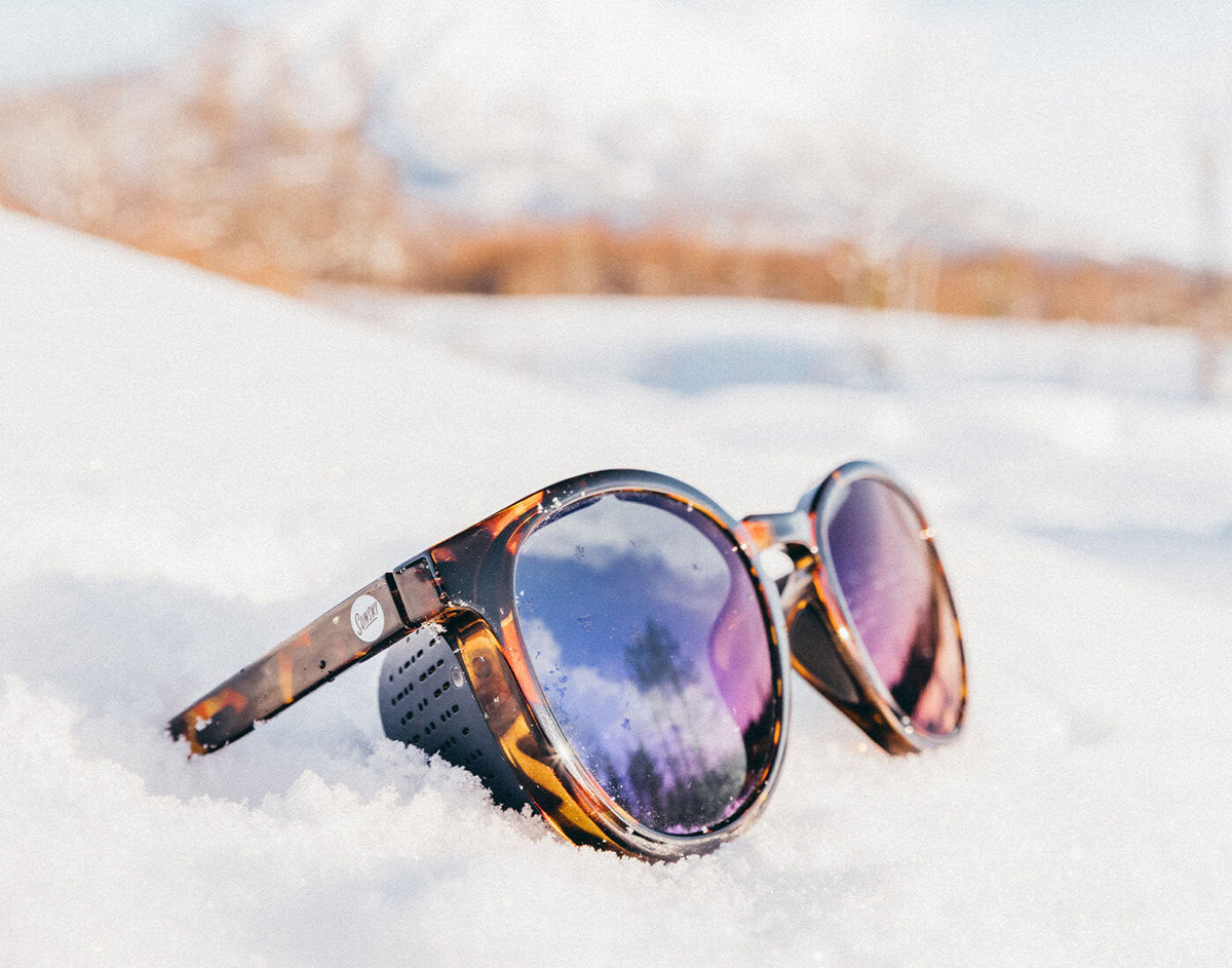 STORY Sunglasses with reflective lenses on a snowy surface